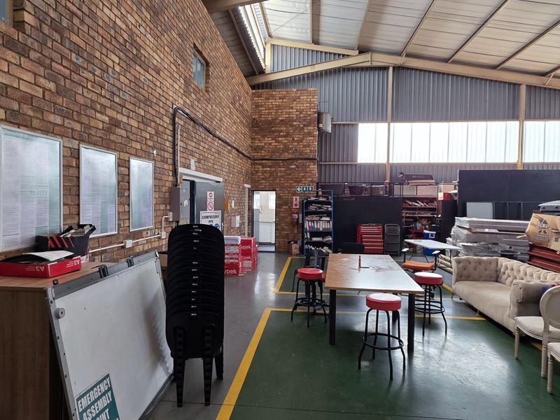 Spacious industrial utility area featuring exposed brick walls, high pitched metal roofing with natural light panels, and durable epoxy-coated flooring.
