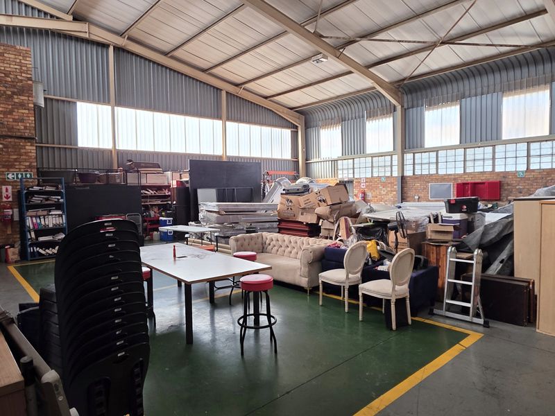 Spacious industrial utility area featuring exposed brick walls, high-clearance steel roof trusses, and durable painted concrete flooring with marked safety zones.