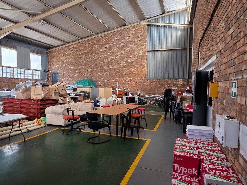 Spacious industrial utility area featuring exposed brick walls, high steel roof trusses, and durable painted concrete flooring with marked safety zones.