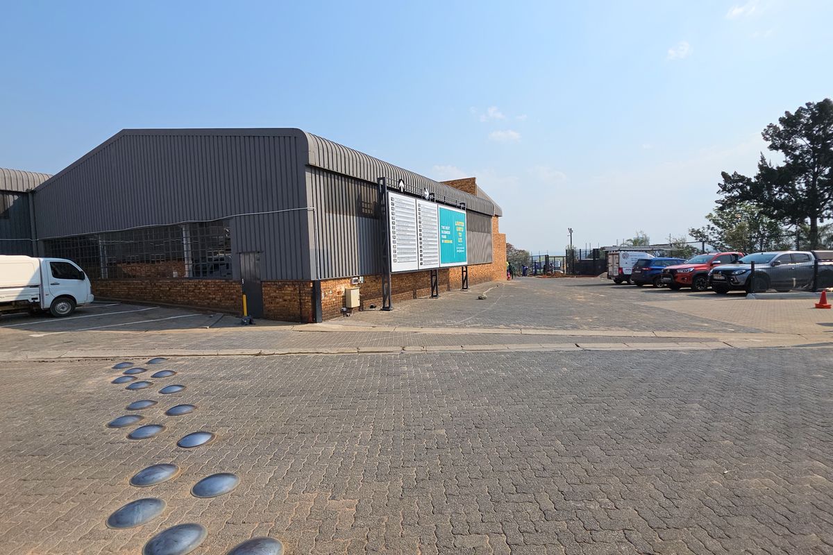 Exterior view of an industrial property featuring corrugated metal cladding, brick base, and a paved parking area with signage.