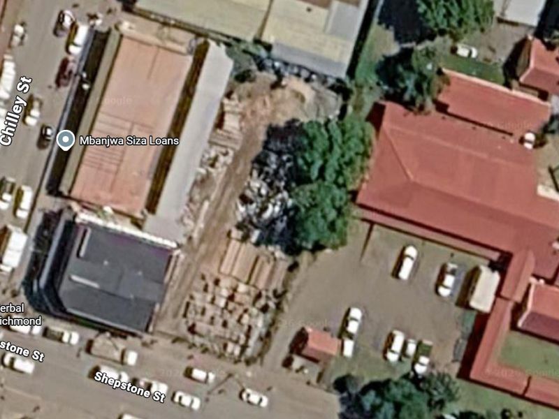 Aerial view of the commercial vacant land site situated between existing buildings with street access.