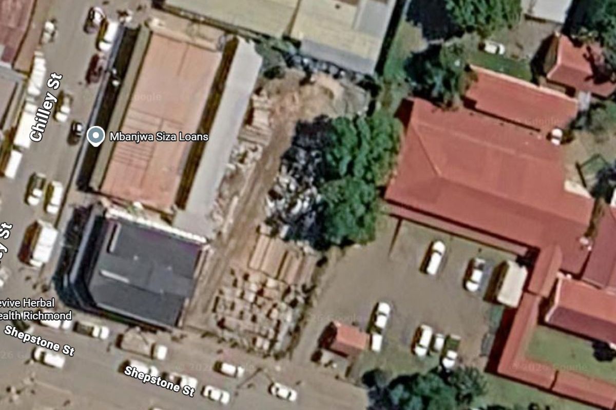 Aerial view of the commercial vacant land site situated between existing buildings with street access.