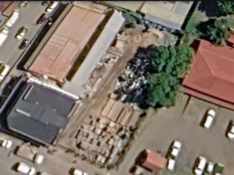 An aerial view of a vacant commercial land plot situated within an established urban area.