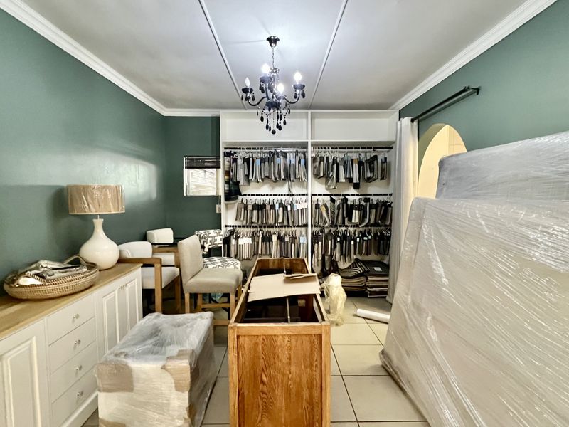 A functional office or showroom space featuring built-in cabinetry, tiled flooring, and decorative crown molding, currently utilized for fabric sample storage.