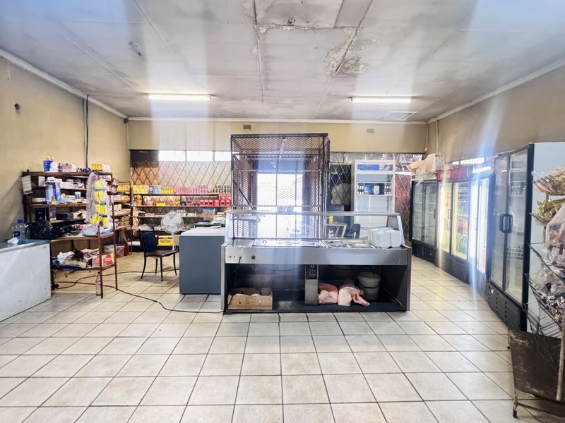 A commercial retail space featuring tiled flooring, fluorescent lighting, and built-in refrigeration units, currently set up for food service or grocery operations.