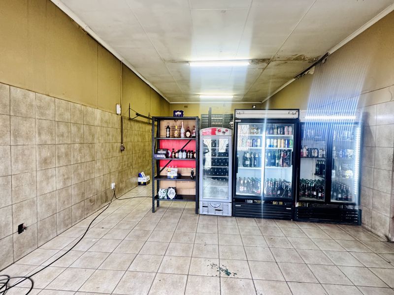 Commercial retail space featuring tiled flooring, wall tiling, and built-in refrigeration units, suitable for a convenience store or beverage outlet.