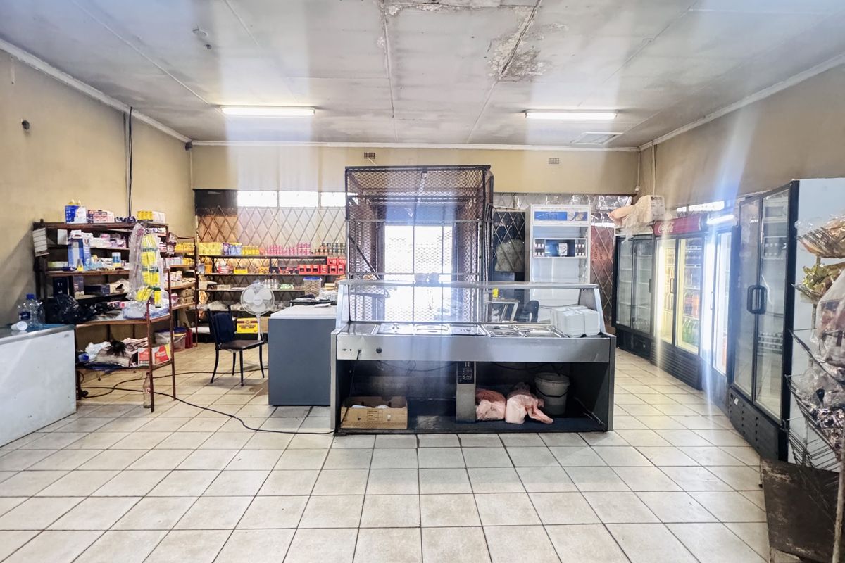 A commercial retail space featuring tiled flooring, fluorescent lighting, and built-in refrigeration units, currently set up for food service or grocery operations.