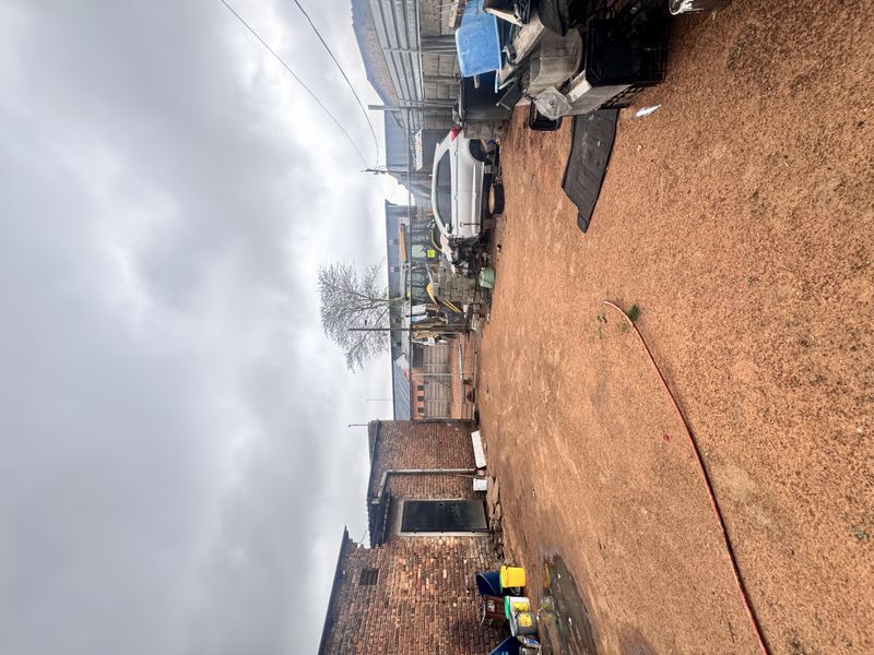 An expansive, unpaved outdoor yard area featuring exposed brick walling and perimeter fencing, suitable for industrial or storage use.