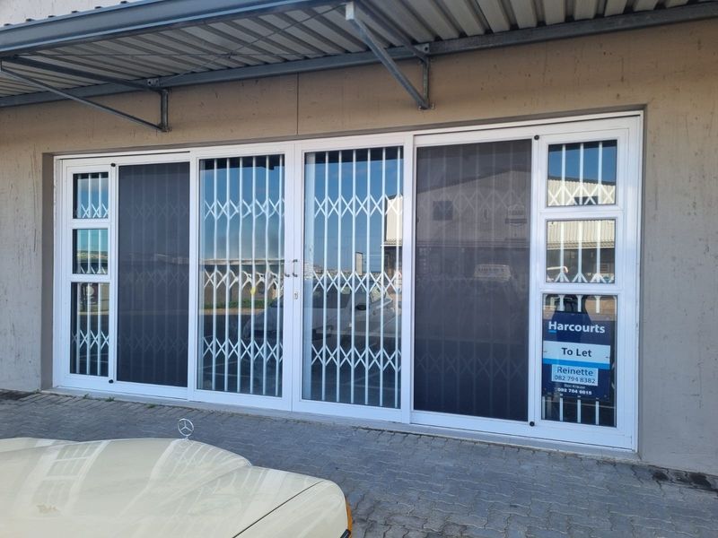Front entrance of the restaurant featuring large sliding glass doors with integrated security gates and a protective metal awning.