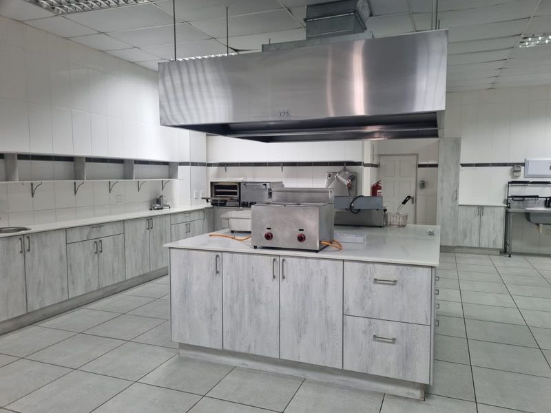 A well-maintained commercial kitchen featuring stainless steel extraction, tiled surfaces, and ample built-in cabinetry for professional food preparation.