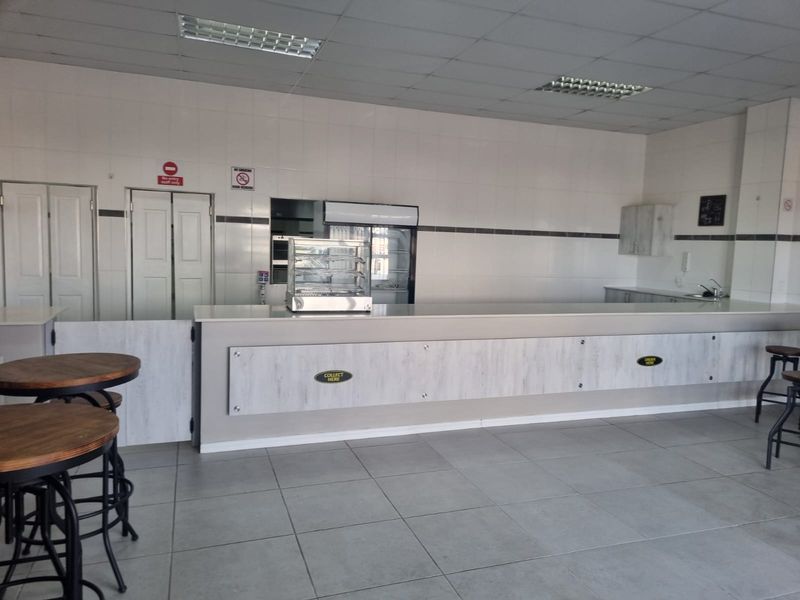 A clean, functional restaurant service area featuring a long service counter, tiled walls, and durable floor tiles, suitable for efficient food service operations.
