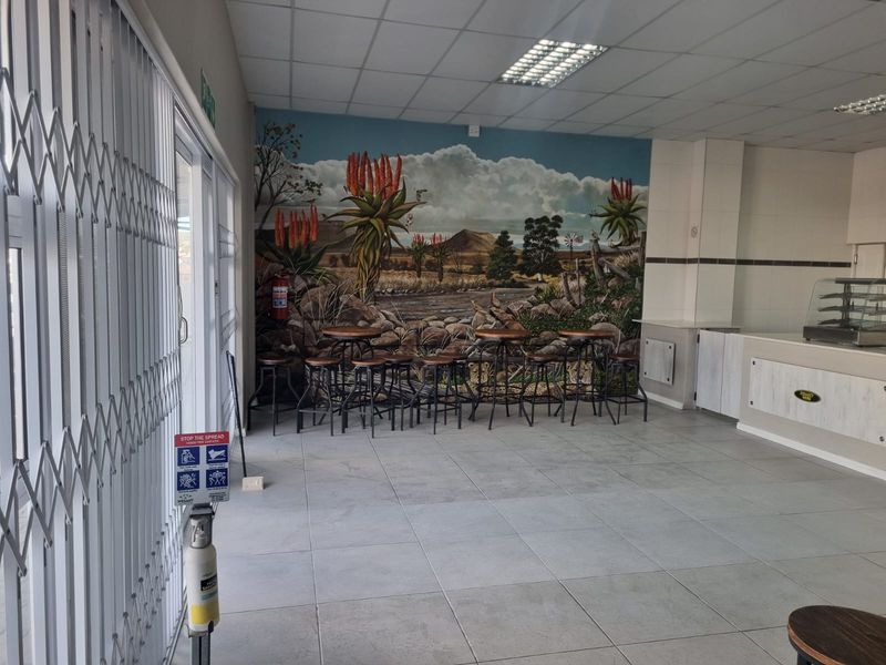 Open plan restaurant interior featuring tiled flooring, drop ceiling, and a service counter area with a decorative mural wall.