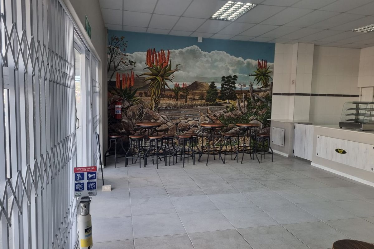 Open plan restaurant interior featuring tiled flooring, drop ceiling, and a service counter area with a decorative mural wall.