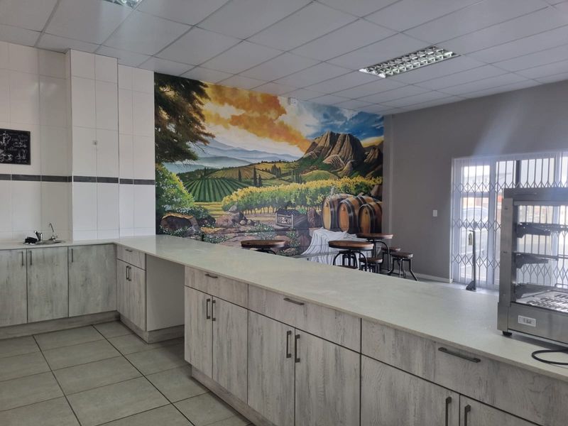 Open plan restaurant area featuring built-in service counters with laminate finishes, tiled flooring, drop ceiling, and a decorative mural wall.