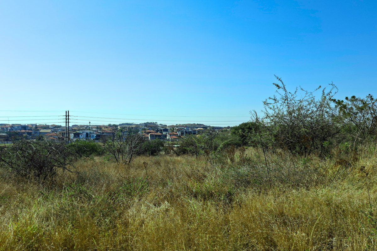 A view of the vacant commercial land with surrounding residential development and overhead power lines visible in the distance.