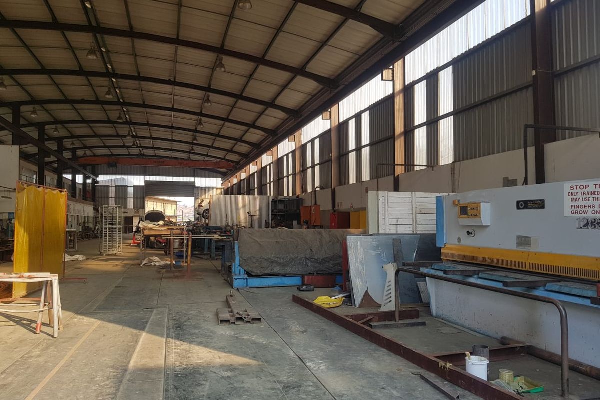 Spacious industrial warehouse facility featuring a steel portal frame, high ceilings with natural light panels, and durable concrete flooring suitable for manufacturing or storage.