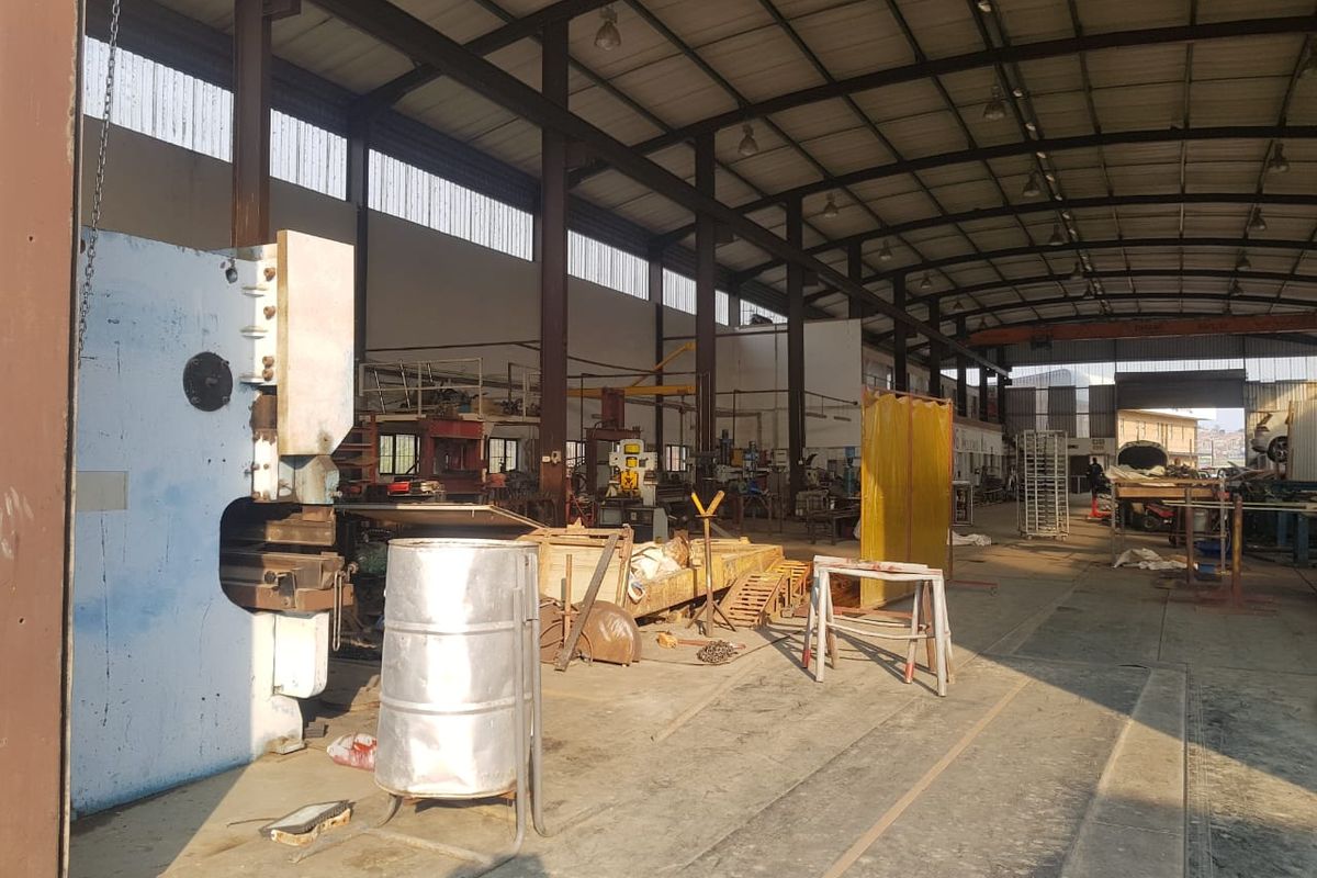 Spacious industrial workshop featuring a steel portal frame structure, concrete flooring, and high-level clerestory windows providing natural light.