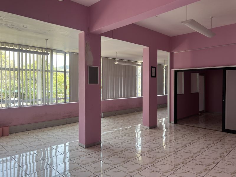 An open-plan commercial space featuring tiled flooring, structural columns, and large windows with vertical blinds, currently vacant and ready for customization.
