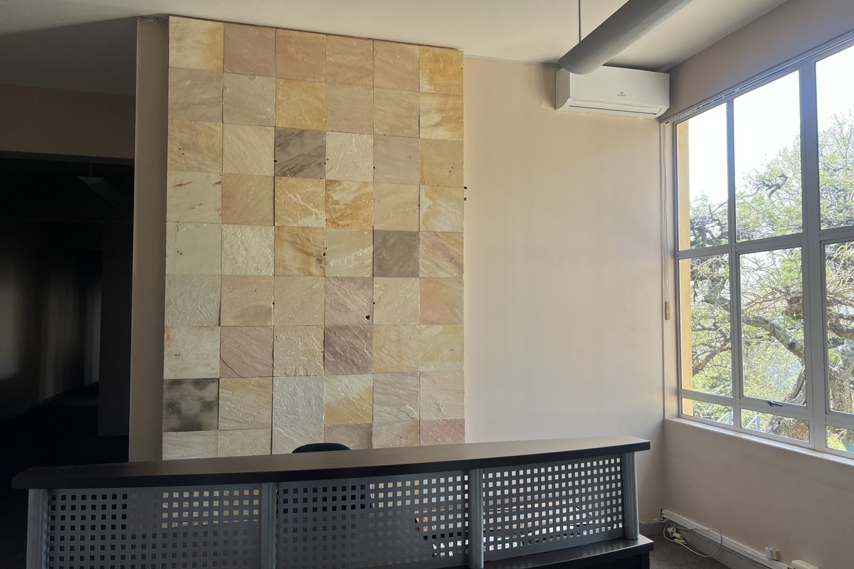 A bright office space featuring a decorative stone feature wall, large windows for natural light, and a built-in reception desk.