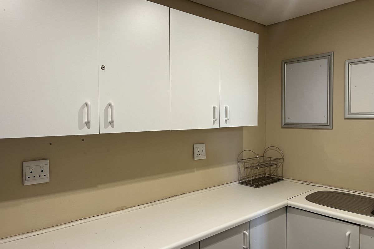 A functional scullery area featuring built-in cabinetry, a laminate countertop, and a stainless steel sink, providing practical utility space.