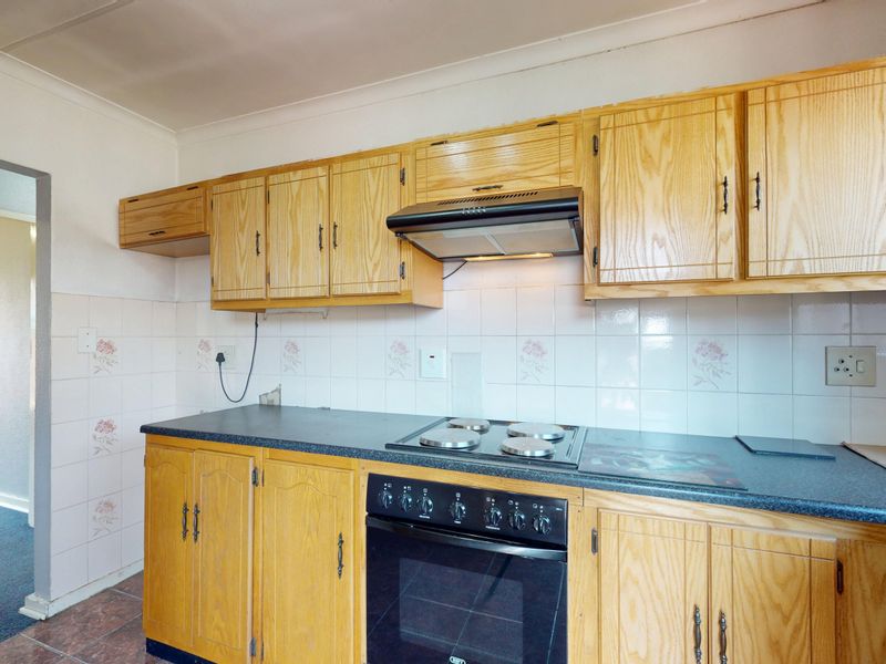 A functional kitchen featuring traditional wooden cabinetry, a dark laminate countertop, and integrated cooking appliances with a tiled backsplash.