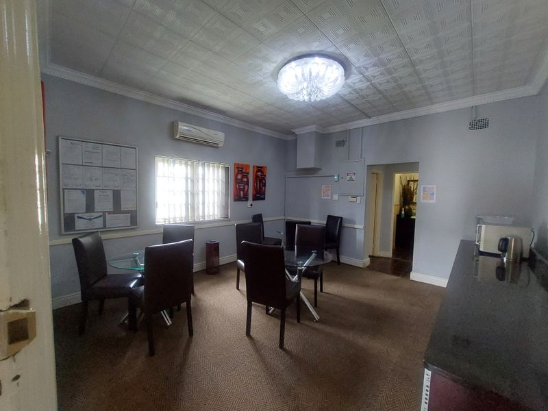 A functional commercial break room or office space featuring a kitchenette area, carpeted flooring, and a decorative ceiling.