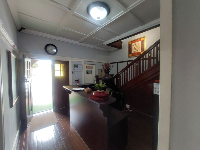 Welcoming commercial entry area featuring a built-in reception desk, timber staircase, and classic coffered ceiling detail.