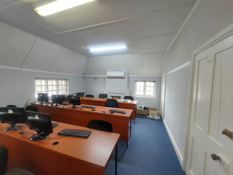 A functional commercial office space featuring multiple workstations, a wall-mounted air conditioning unit, and a fireplace, suitable for a professional work environment.