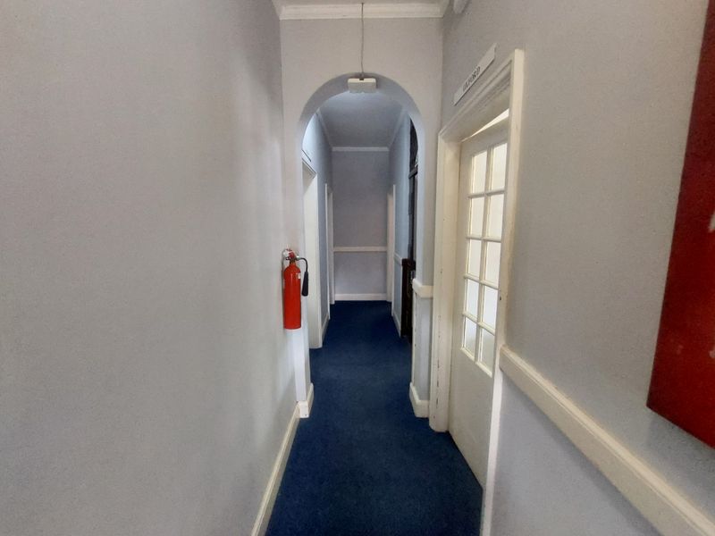 A commercial hallway featuring an arched transition, blue carpeting, and a wall-mounted fire extinguisher.