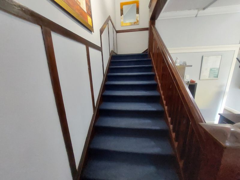 A staircase featuring dark wood handrails and trim with blue carpeted steps, leading to an upper level landing.