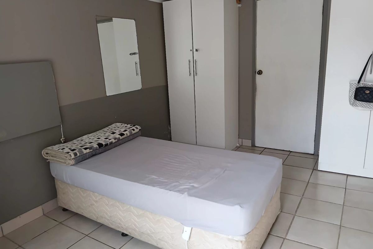 A functional bedroom space featuring tiled flooring and built-in wardrobe storage, suitable for office or residential use.