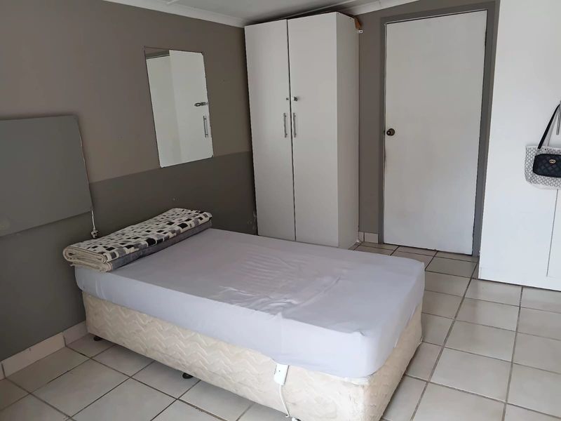A functional bedroom space featuring tiled flooring and built-in wardrobe storage, suitable for office or residential use.