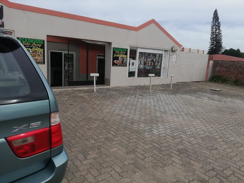 Front exterior view of a commercial office or retail property featuring a paved parking area and shopfront entrance.
