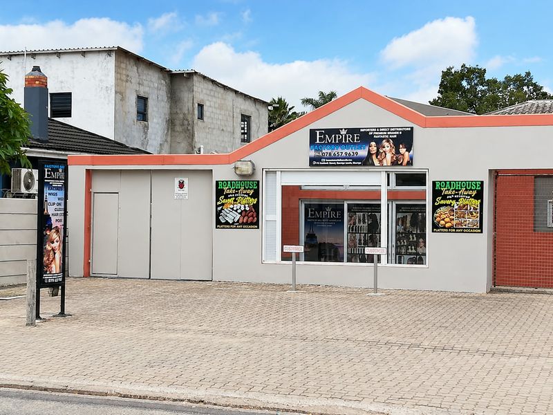 Front exterior view of a commercial office or retail space featuring paved parking, large display windows, and prominent business signage.