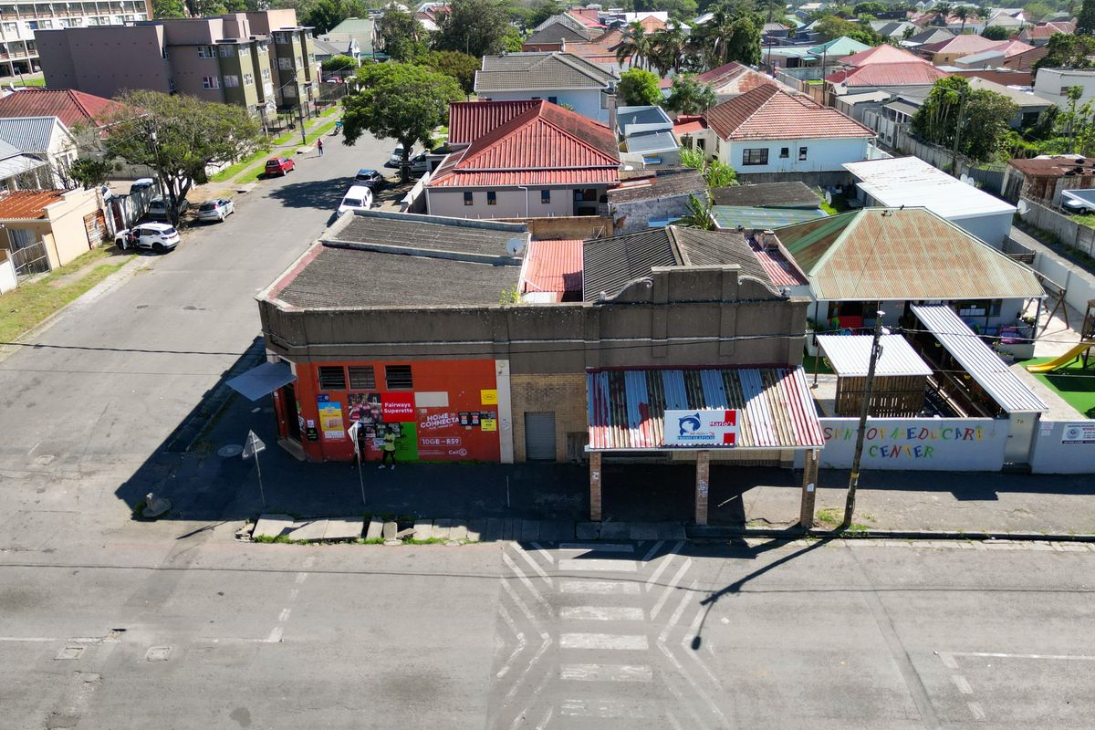 Aerial view of a commercial property featuring a corrugated metal roof, covered entrance canopy, and street-level access in a suburban neighborhood setting.