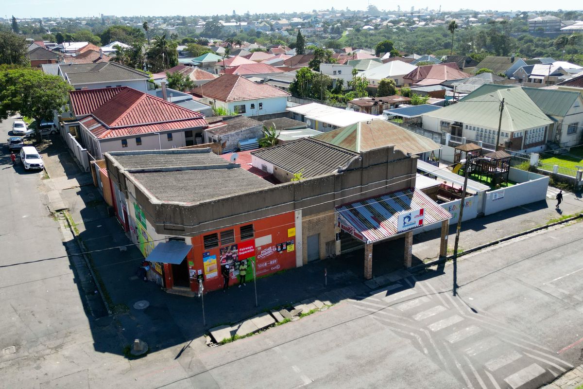 Aerial view of a commercial corner property featuring a flat roof, covered entrance, and street-level access in a suburban neighborhood setting.