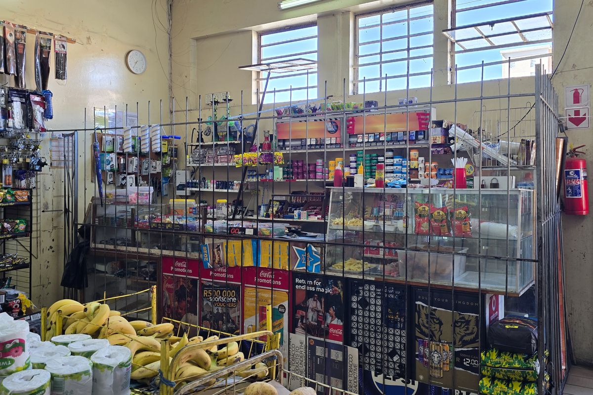 Commercial retail space featuring a secure service counter, industrial-style windows, and functional retail shelving units.