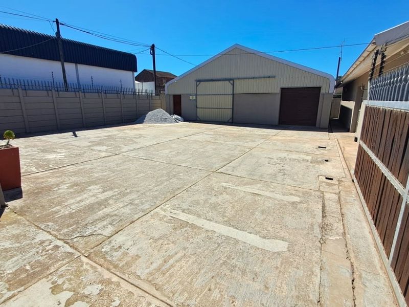 Spacious paved exterior yard area featuring a large industrial-style storage building with sliding doors and secure perimeter walling.