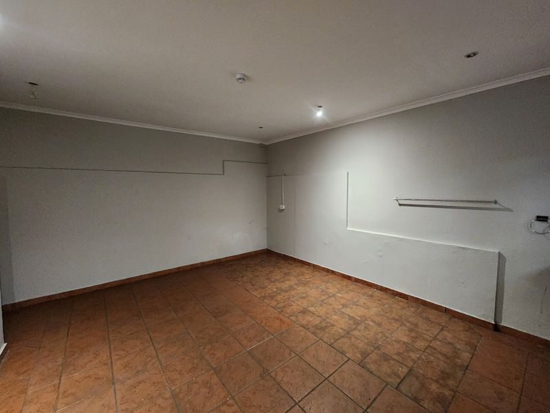 An empty utility space featuring tiled flooring, recessed lighting, and wall-mounted fixtures, suitable for various industrial or storage purposes.