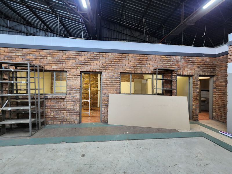 Industrial utility space featuring exposed brick walls, high-ceiling steel structure, and multiple access points, suitable for workshop or storage use.