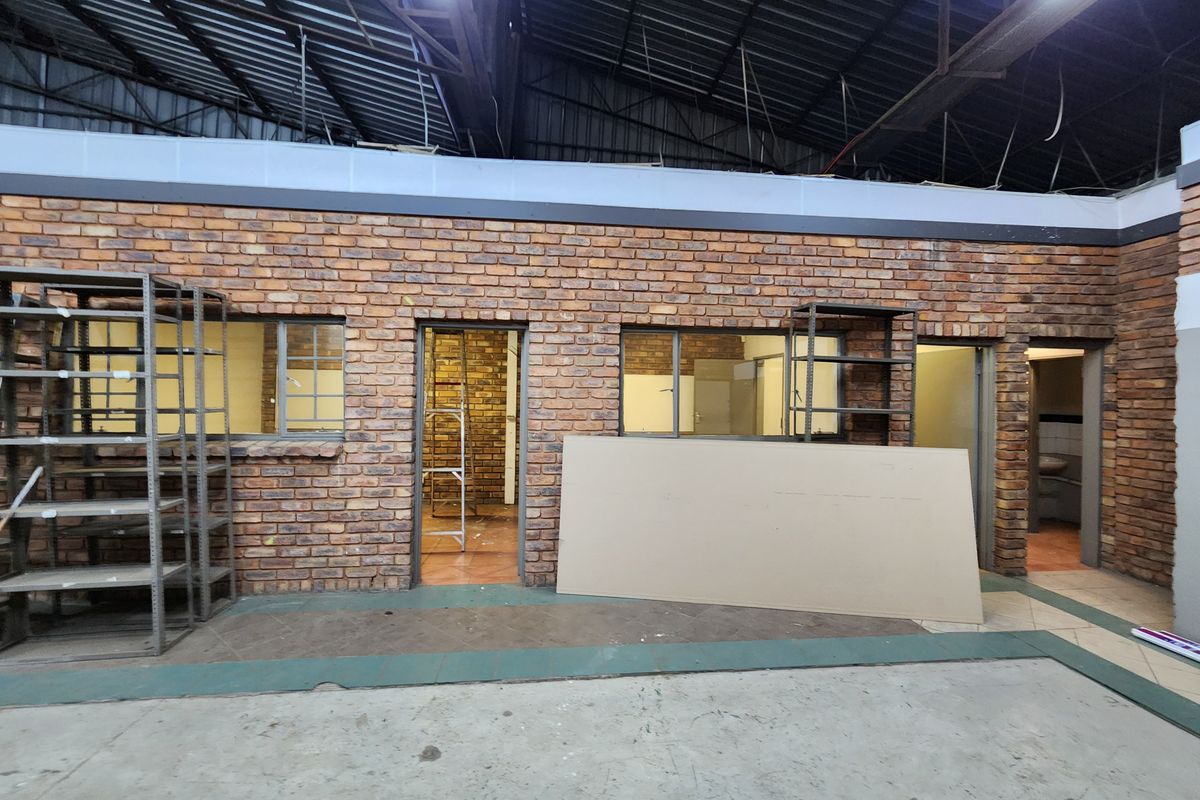 Industrial utility space featuring exposed brick walls, high-ceiling steel structure, and multiple access points, suitable for workshop or storage use.