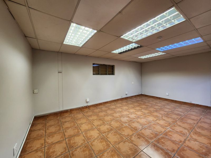 An empty office space featuring a suspended ceiling with recessed lighting, ceramic tiled flooring, and multiple electrical power points.