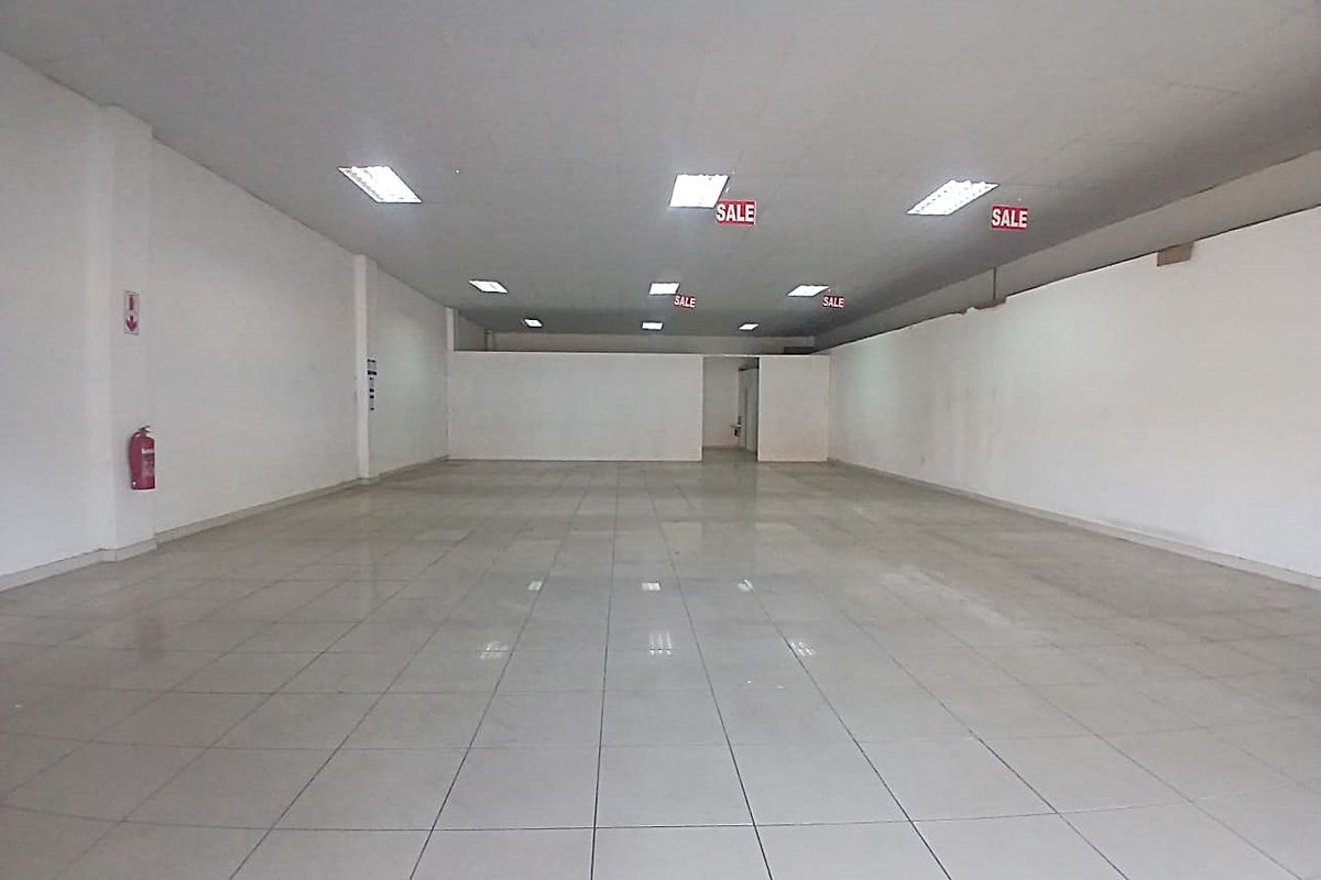 A spacious, empty retail unit featuring tiled flooring, a suspended ceiling with recessed lighting, and neutral white walls, ready for custom fit-out.