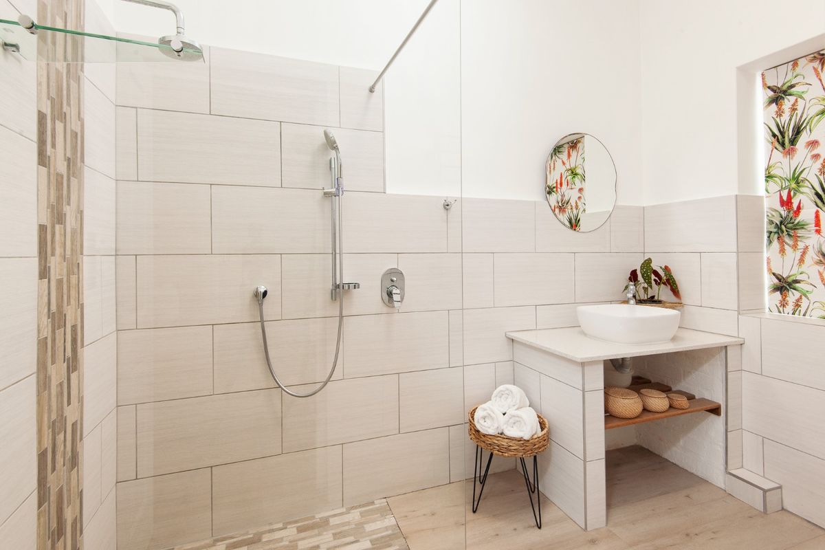 Modern bathroom featuring a spacious walk-in shower with glass screen, contemporary vessel sink, and neutral tiled finishes.