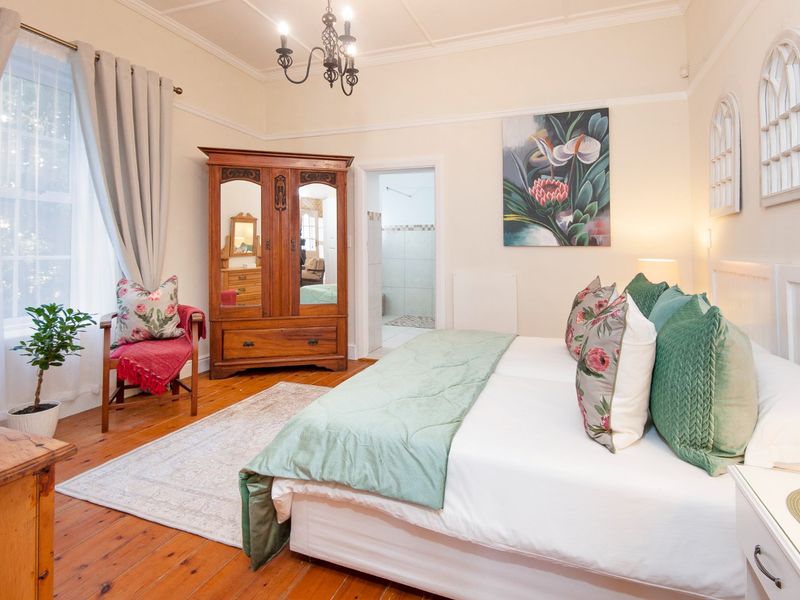 A well-maintained bedroom featuring original hardwood flooring, high ceilings with coved detailing, and a classic chandelier, offering a warm and inviting atmosphere.