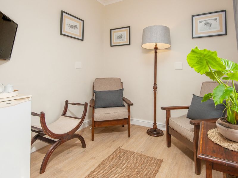 A cozy seating area featuring light wood-look laminate flooring and neutral wall finishes, suitable for a guest house lounge or relaxation space.