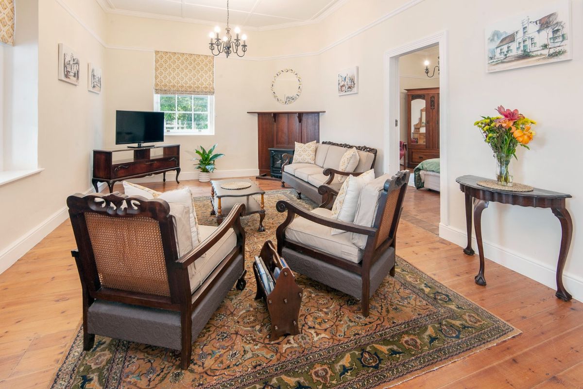 A well-maintained living room featuring original hardwood flooring, a classic fireplace mantel, and elegant coved ceilings, offering a warm and inviting atmosphere.