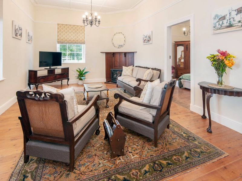 A well-maintained living room featuring original hardwood flooring, a classic fireplace mantel, and elegant coved ceilings, offering a warm and inviting atmosphere.