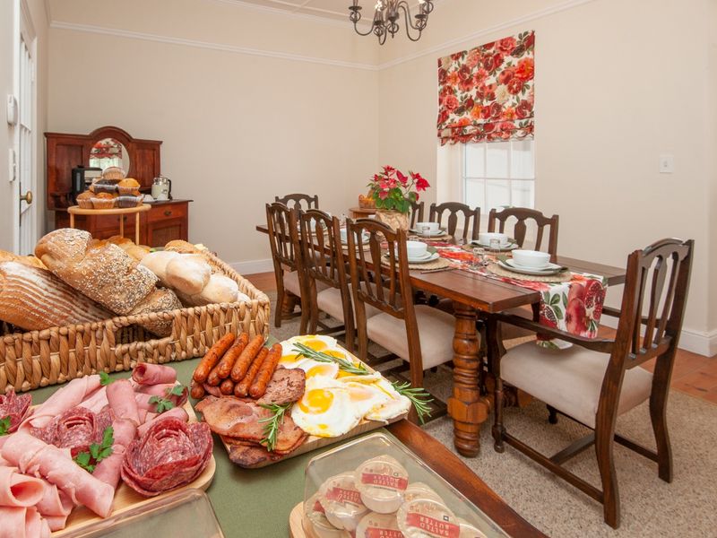 A traditional dining room featuring terracotta flooring, crown molding, and a classic chandelier, providing a warm and inviting space for guest meals.