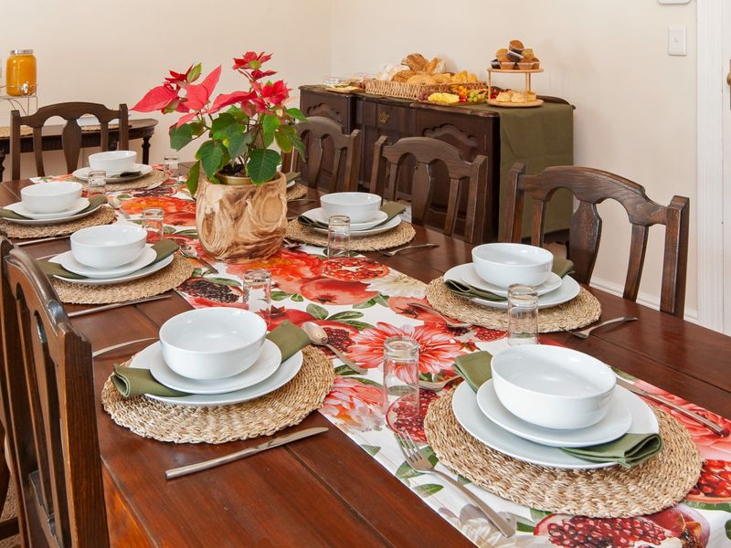 A formal dining room set for a meal, featuring a large wooden dining table and matching chairs.